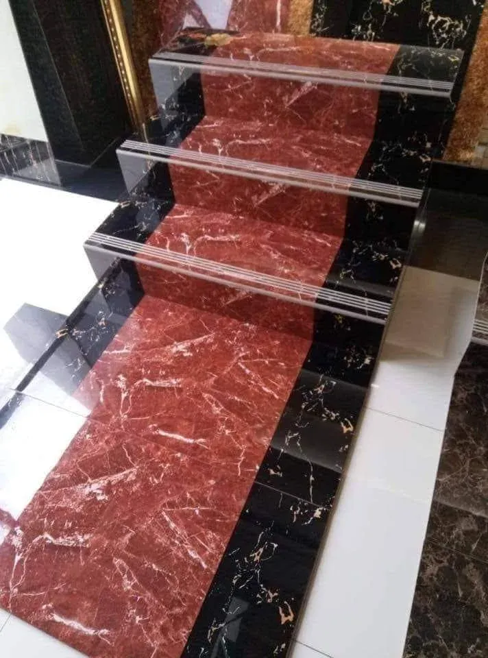Red veined marble runner between black-and-gold marble sides on a staircase, with grooved metal nosing on every step