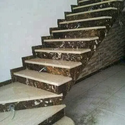 Staircase with dark brown veined marble risers, cream marble treads and winder steps at the bottom
